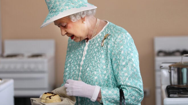 Britain's Queen Elizabeth II looks at homemade scones as she visits the kitchen at Clontarf Aboriginal College in Perth on October 27, 2011. The queen, who arrived in Perth on October 26, will officially open the 54-nation Commonwealth Heads of Government Meeting (CHOGM) on October 28 where revamping succession to the British throne will be discussed, concluding a 10-day tour of her antipodean realm. AFP PHOTO / POOL / SHARON SMITH (Photo credit should read SHARON SMITH/AFP via Getty Images)