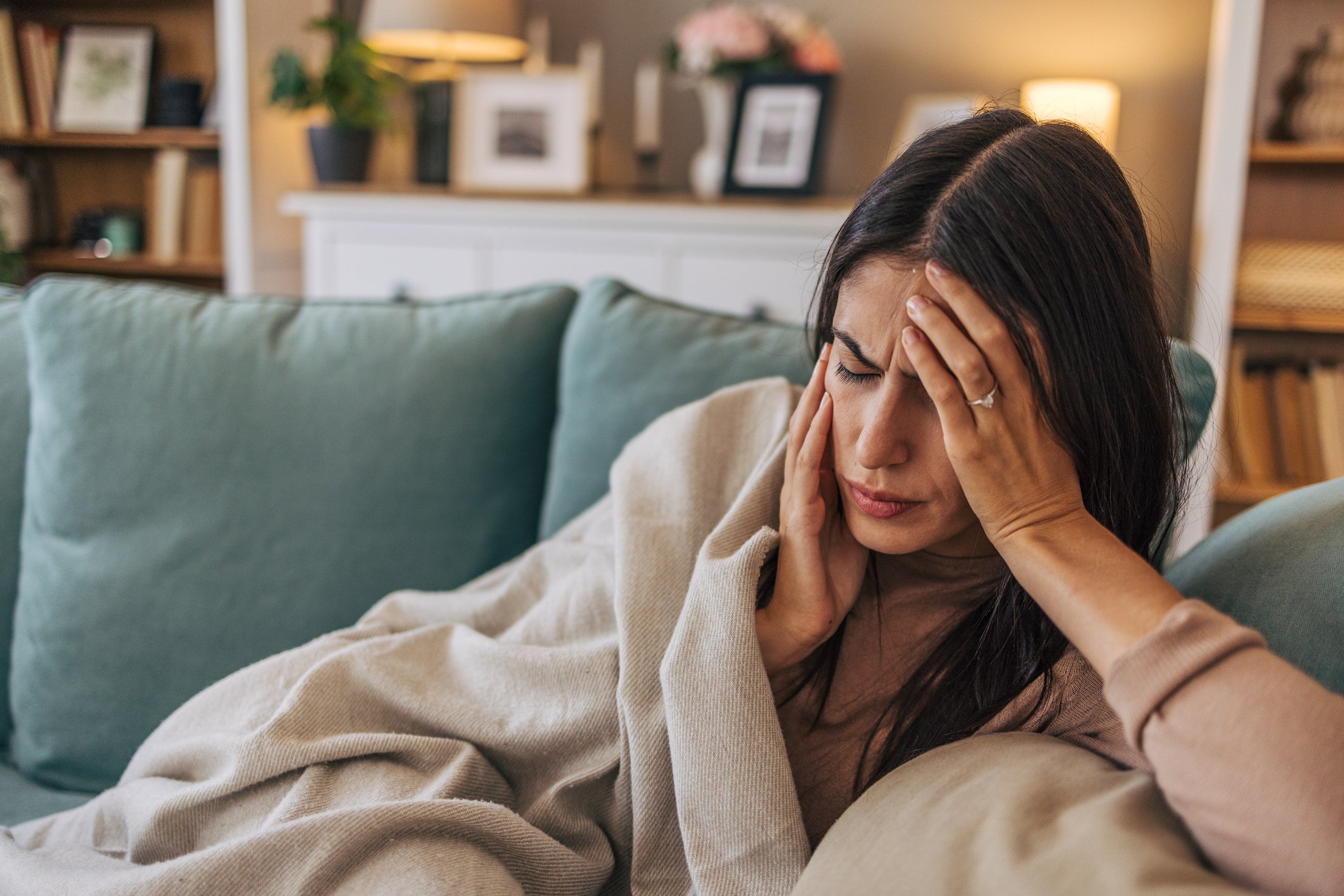 A young woman lying on the sofa in the living room, feeling sick.