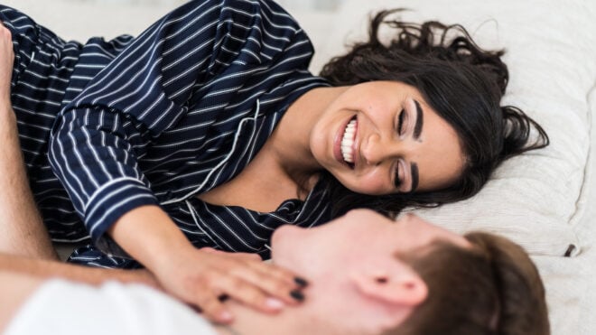 Couple laughing in bed while laying down