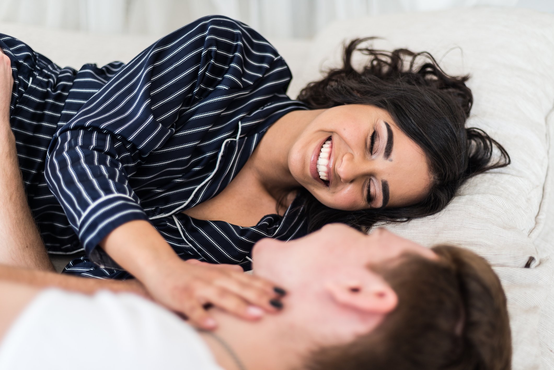Couple laughing in bed while laying down