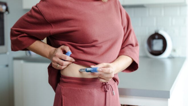 A close-up of a woman self-administering an injection at home