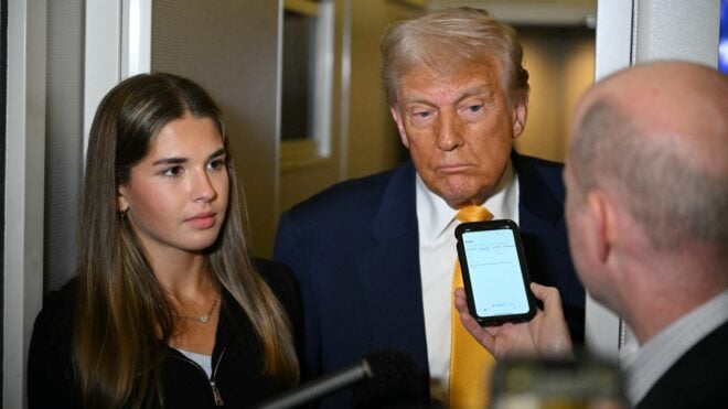 US President Donald Trump (C) listens to reporters as his granddaughter Kai Madison Trump