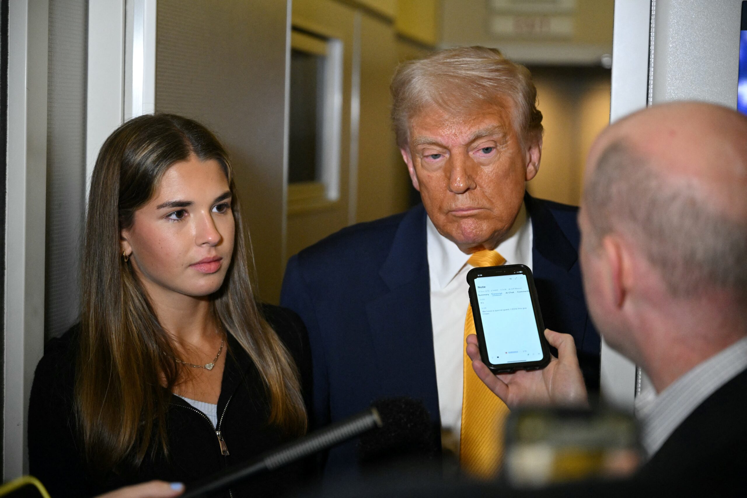 US President Donald Trump (C) listens to reporters as his granddaughter Kai Madison Trump