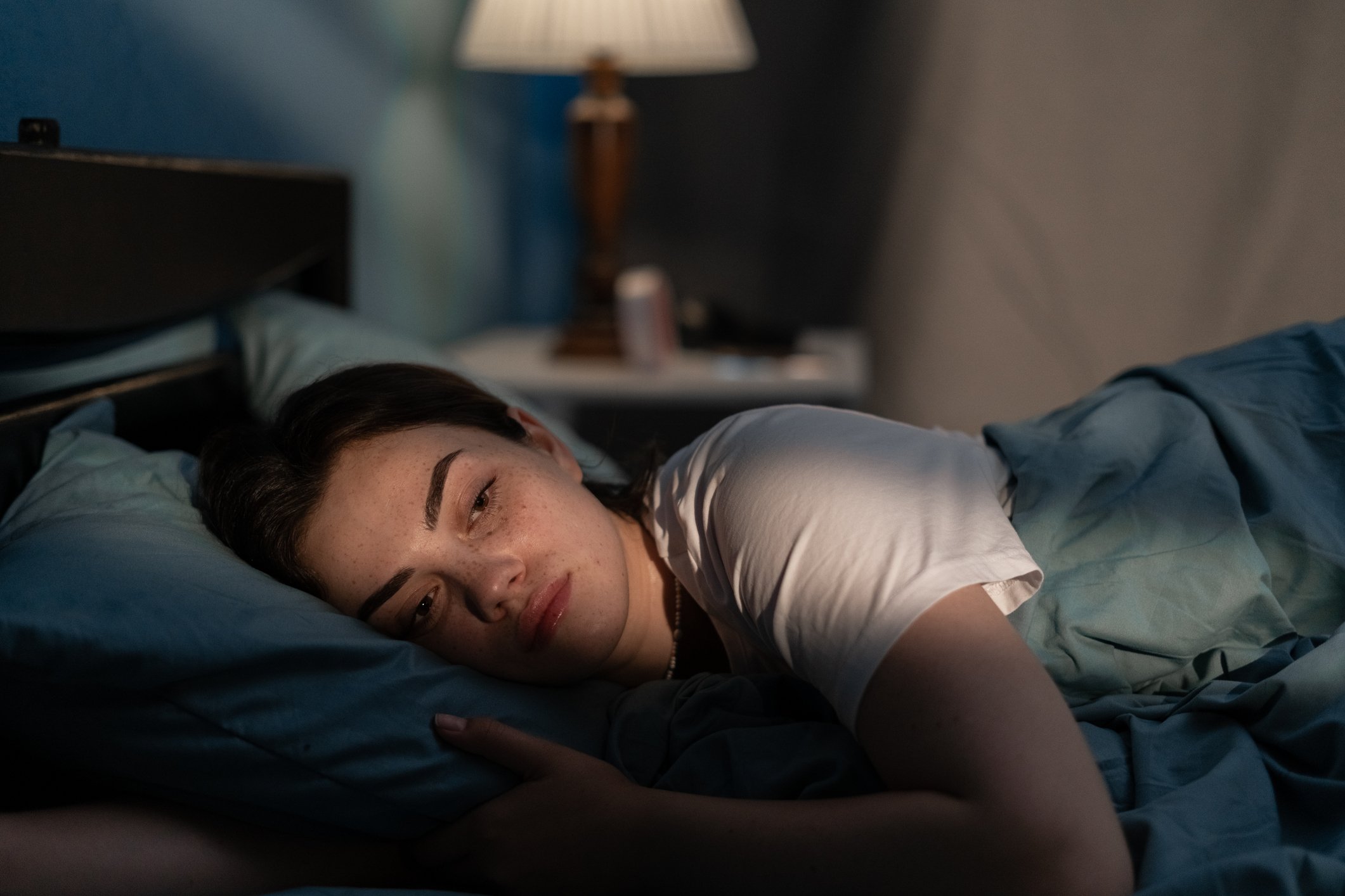 Young sad woman lying in bed awake
