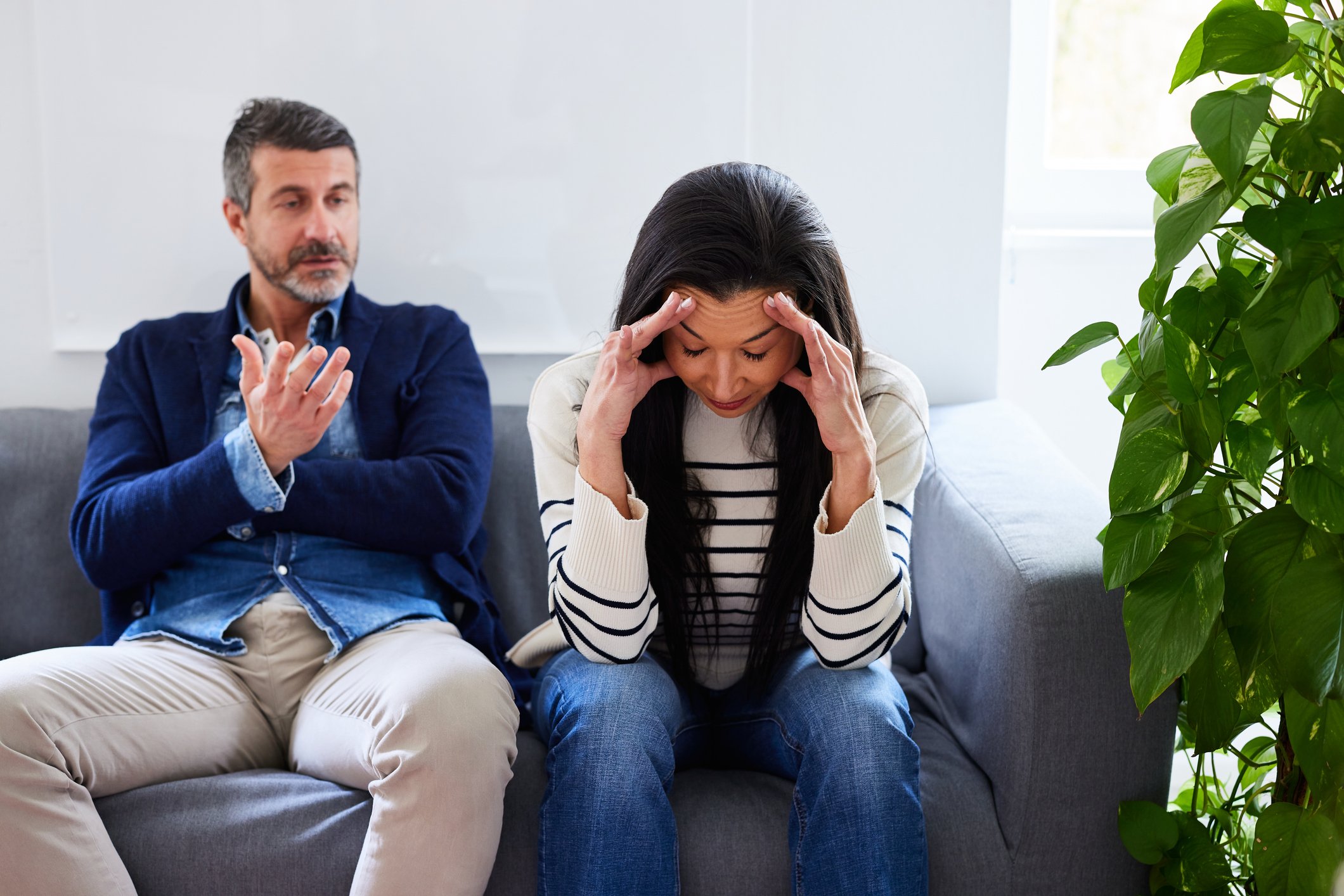 Frustrated wife with husband sitting on couch