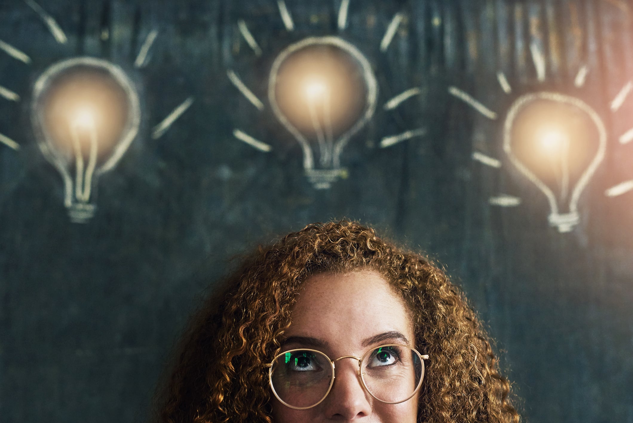 Girl, thinking or blackboard with lightbulb for idea at school, learning or education for future. Female student, glasses or chalkboard with lamp for knowledge in classroom, thought for scholarship