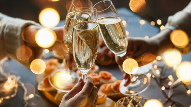 Friends celebrating Christmas or New Year eve party with champagne or sparkling wine.
