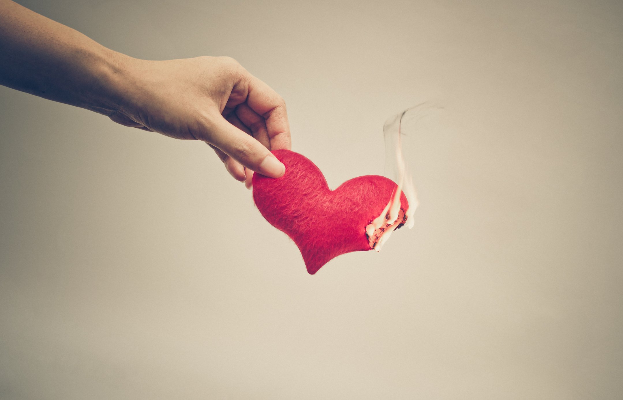 Female hand giving a heart on fire / Dangerous love