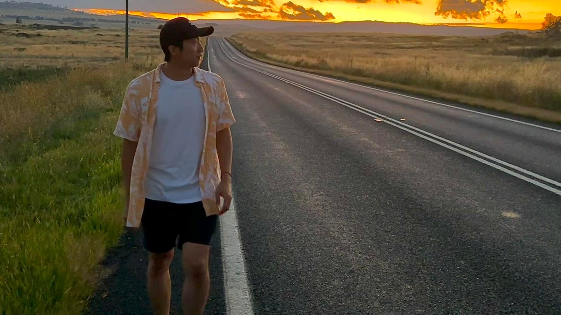 image of a man walking along a road at sunset
