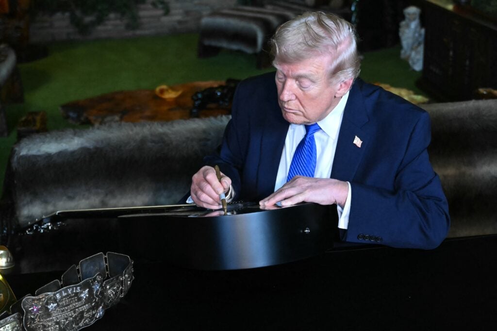 Trump signing replica of Elvis guitar at Graceland