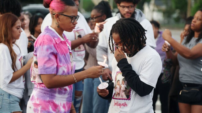 Mourners light candles during a community vigil for 2-year-old Tiana Rae Watts and 1-year-old Jaliyah Katherine Watts