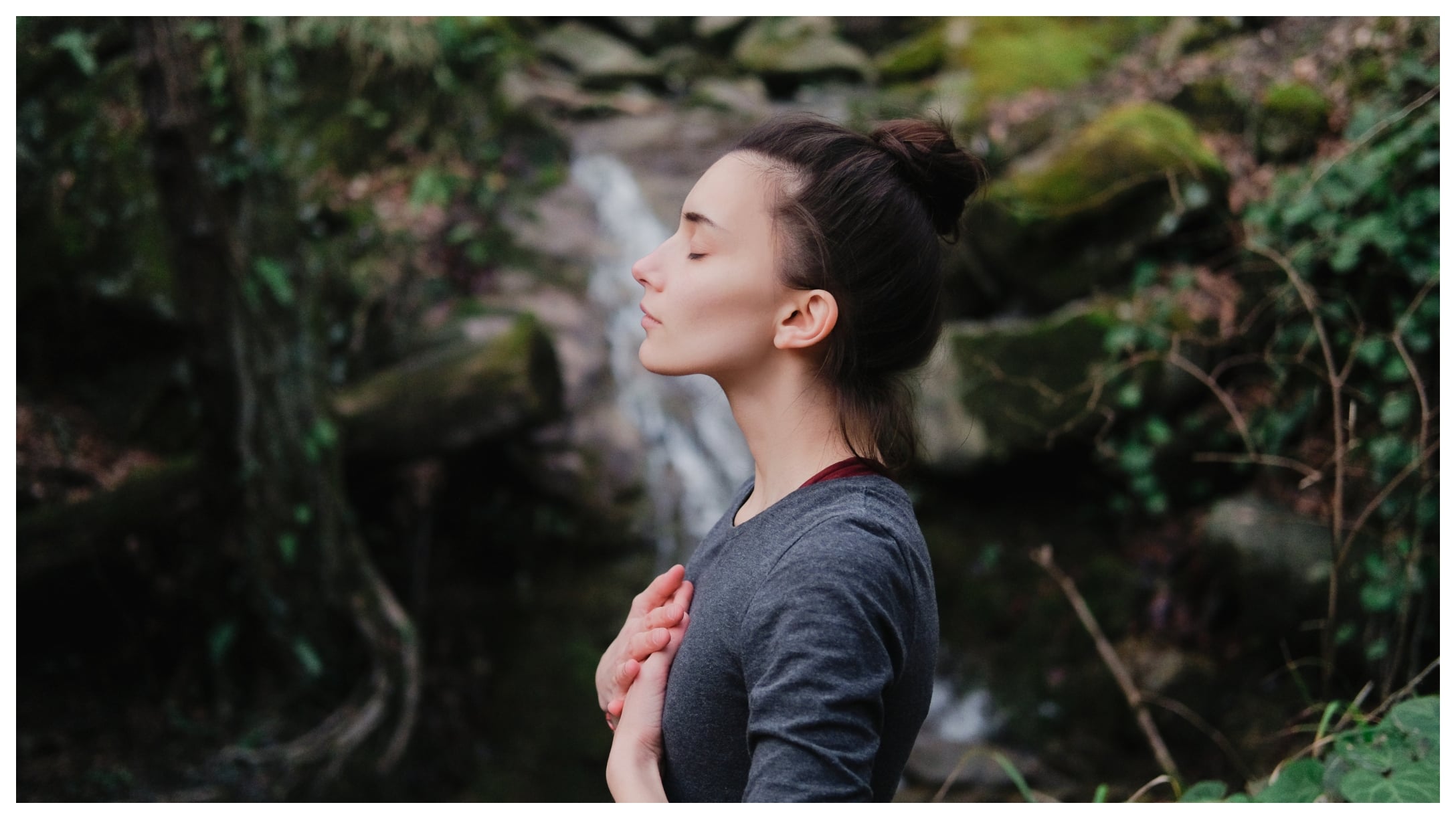 woman meditating by a waterfall