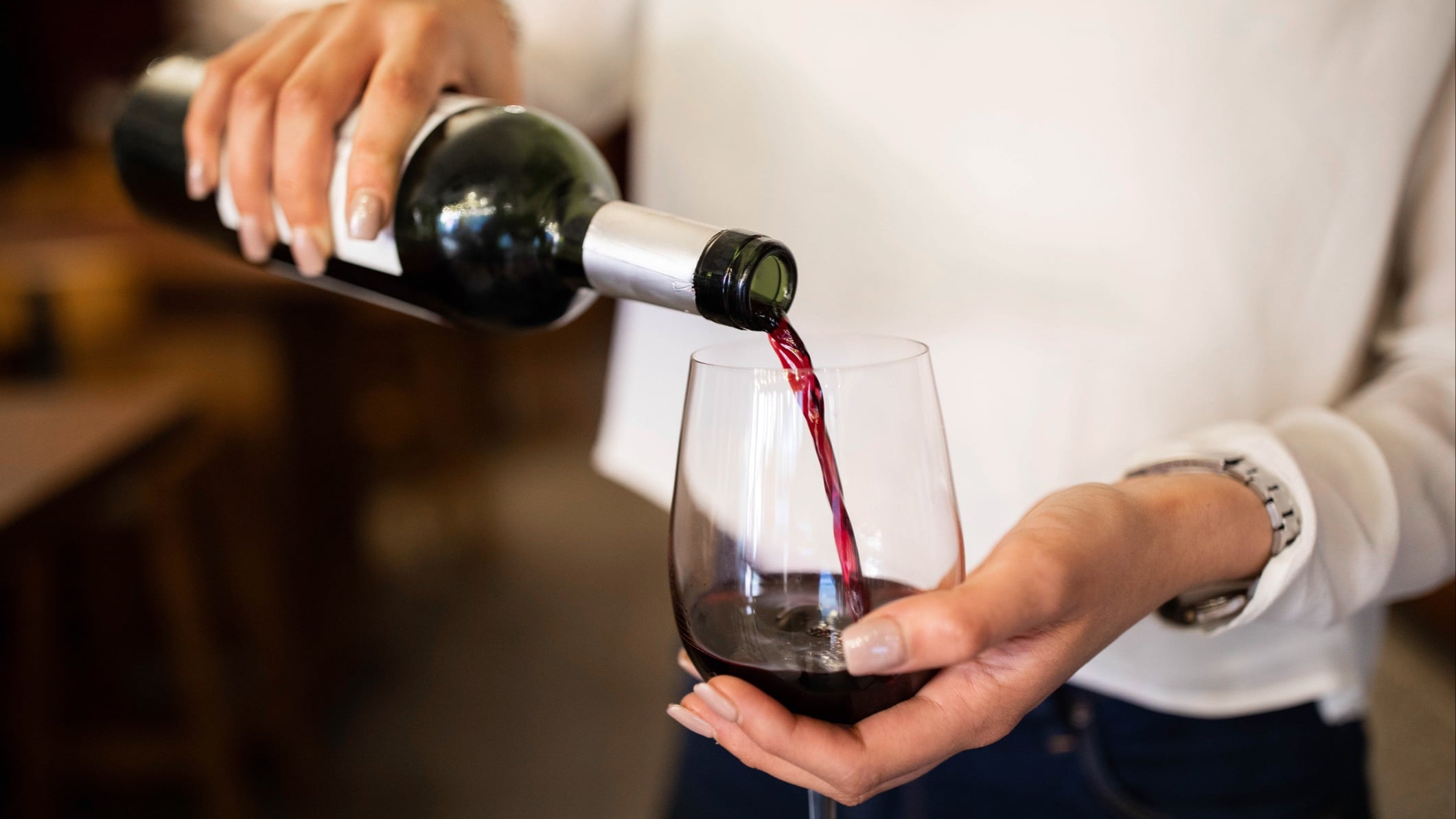 Woman's hands pouring a glass of red wine