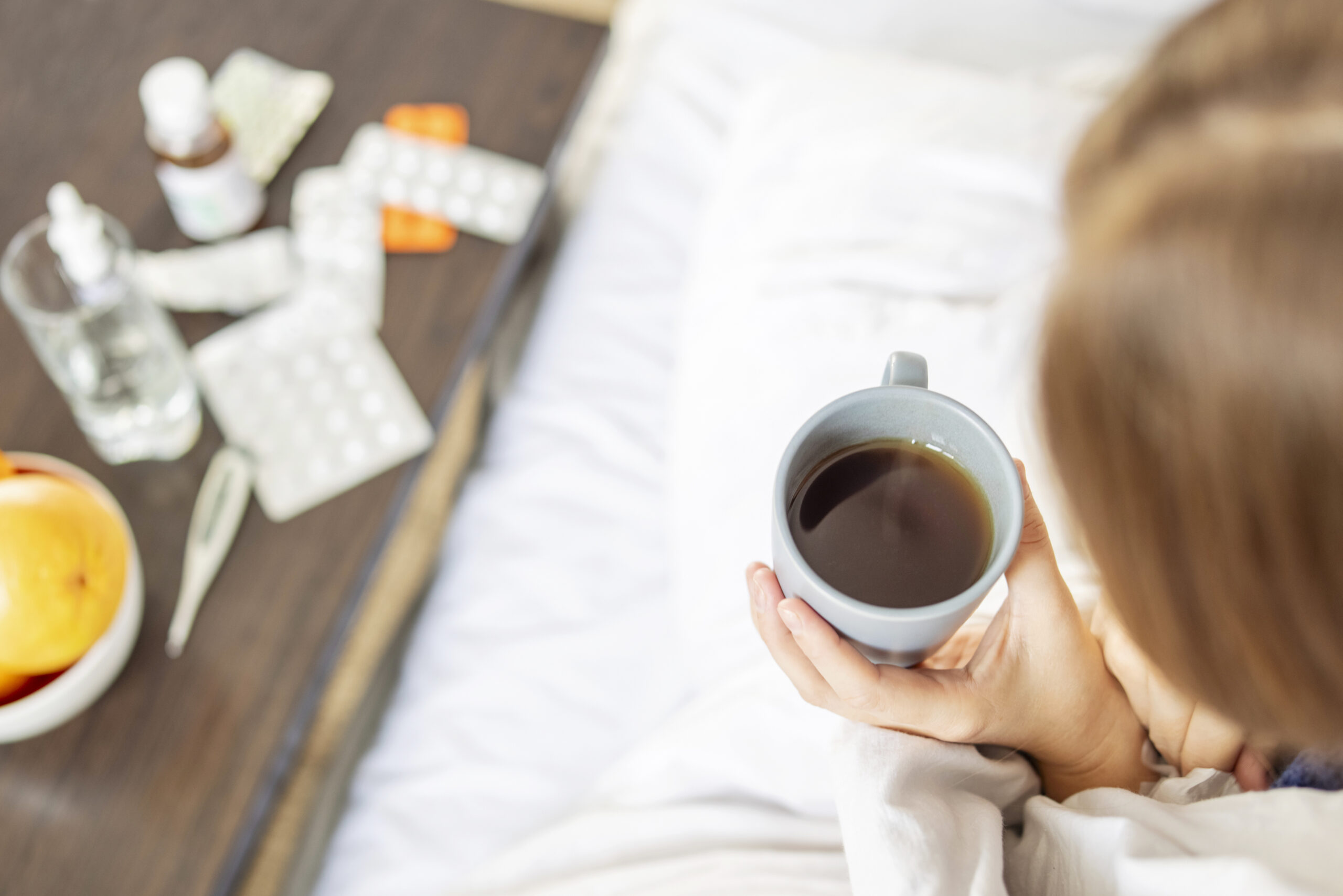 Woman holding mug of coffee in hospital bed