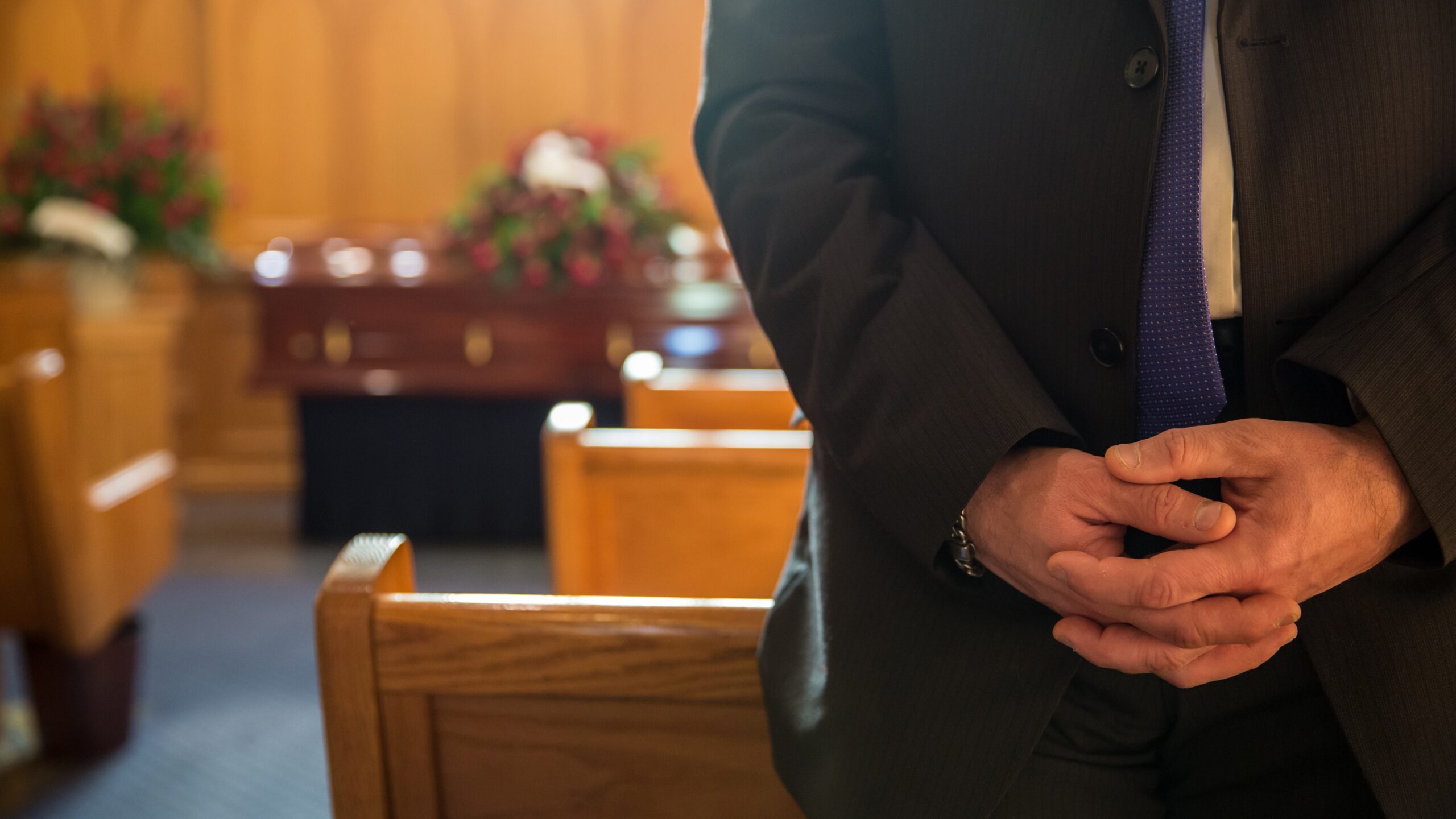 Man with hands behind back in church at funeral