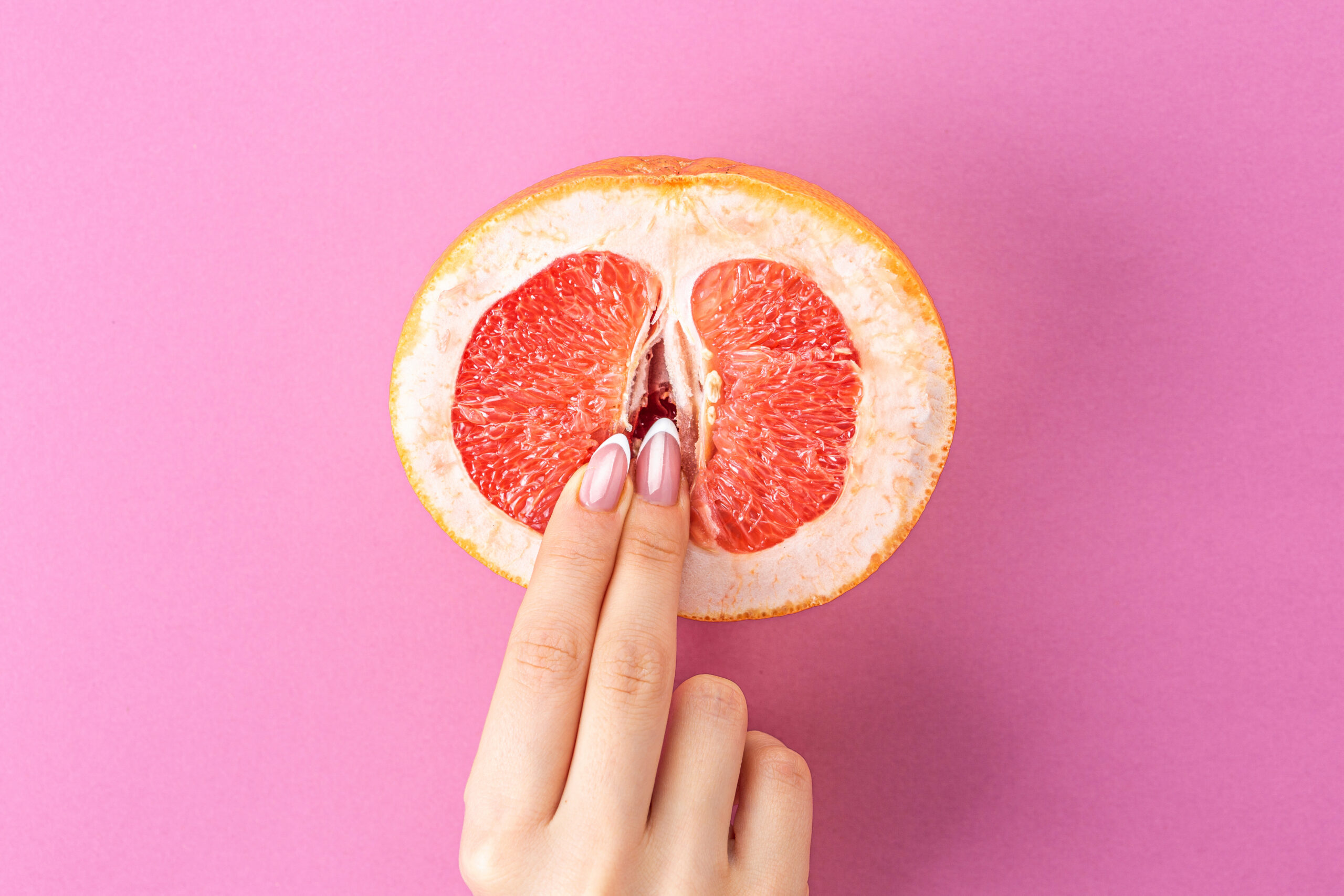 vabbing, fingers on grapefruit on pink background. Sex concept. sexy fruit composition. Vagina symbol.