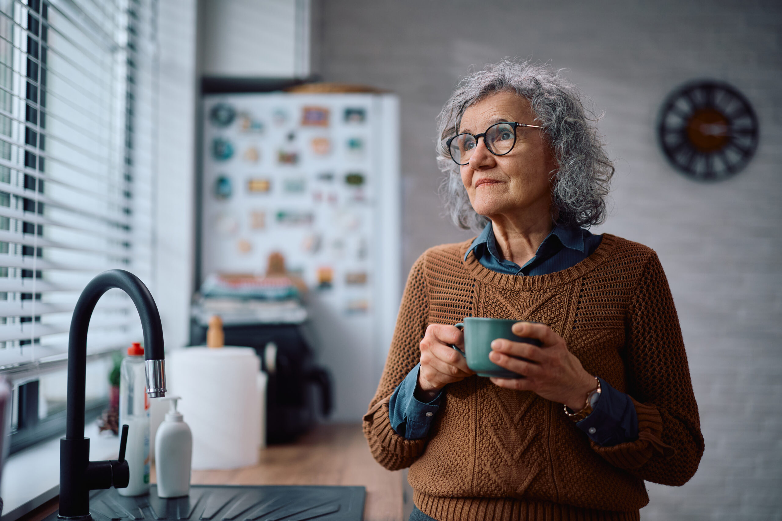 alzheimer's disease, coffee, Thoughtful senior woman looking through the window while having a cup of coffee in the kitchen. Copy space.